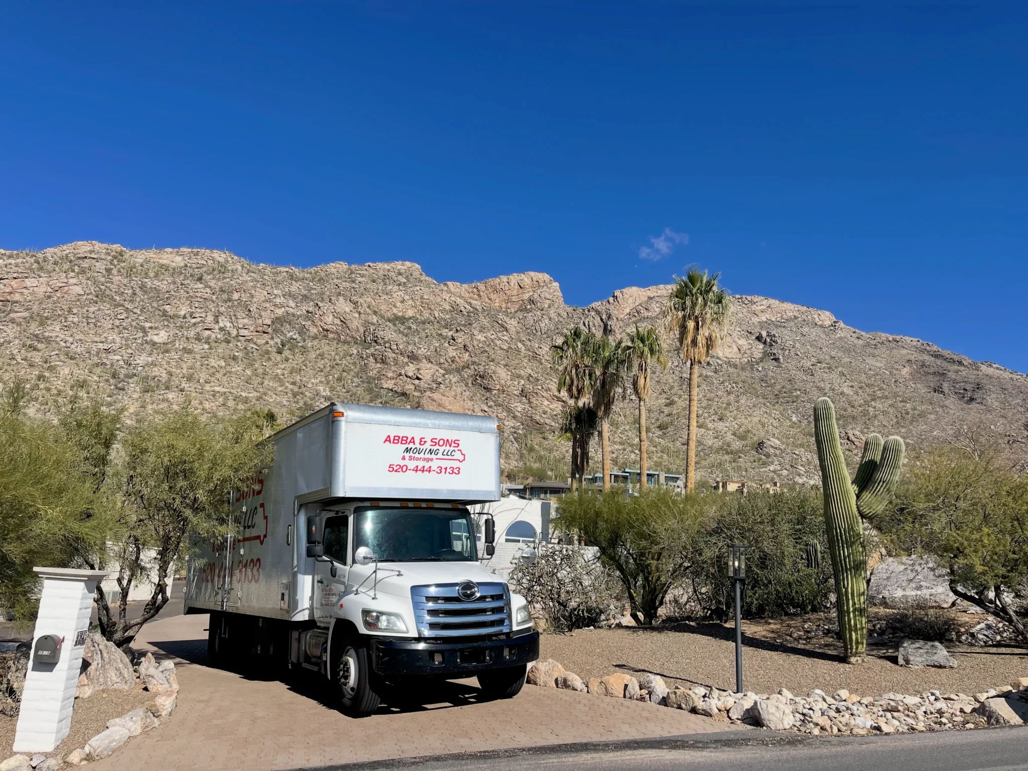 Abba and Sons Moving truck parked in a desert residential driveway with Tucson mountains and cactus in the background