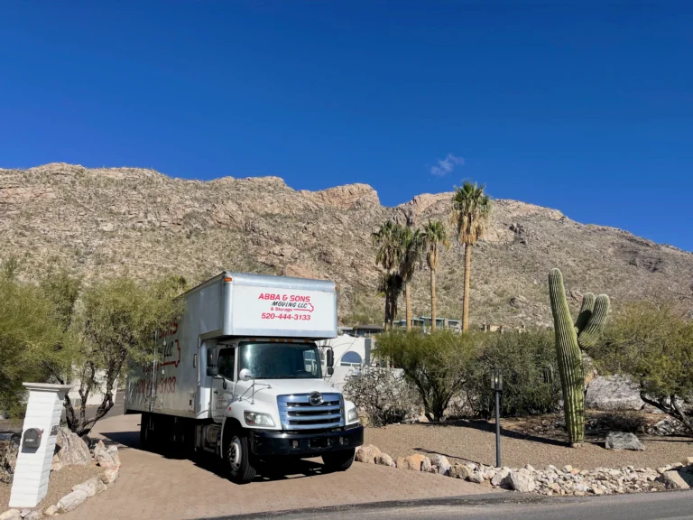 Abba and Sons Moving truck parked in a desert residential driveway with Tucson mountains and cactus in the background