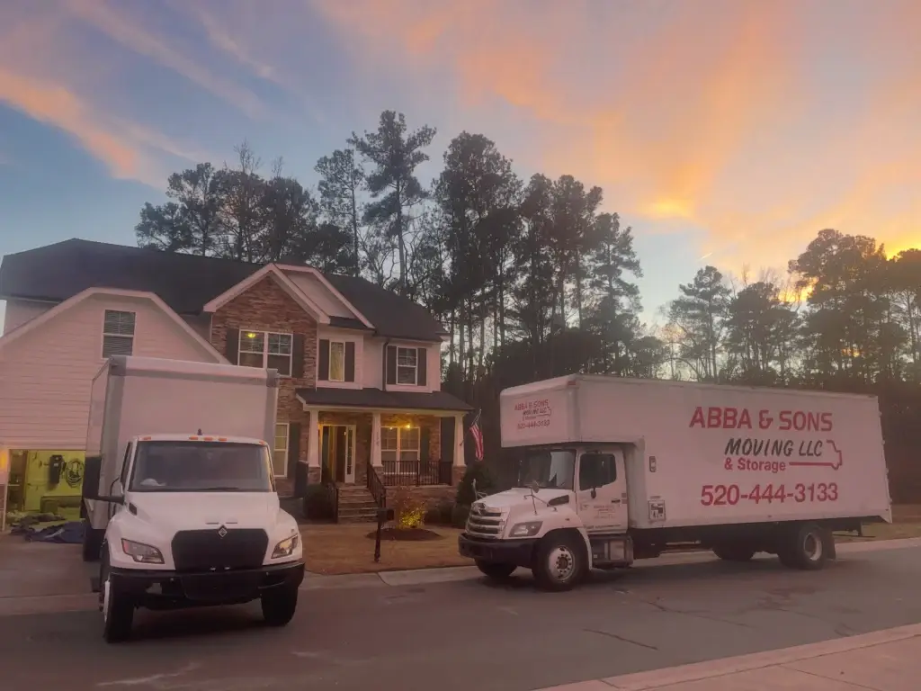 Two Abba and Sons Moving trucks parked outside a house during unloading for a long-distance move